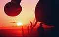 A C-130 Hercules aircraft takes off in the distance as a section of a Military Airlift Command C-5B Galaxy aircraft, foreground, is silhouetted by the morning sun at Grootfontein Logistics Base.