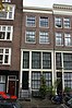 Huis met boven de hoge houten pui 19e-eeuwse gevel onder rechte lijst waarboven een dakvoorschot