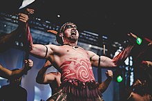 A Maori man performing haka, a ceremonial dance. He is displaying several hallmarks of behavioral modernity including the use of jewelry, application of body paint, music and dance, and symbolic behavior. Festiwal Polka 1 Fot.Wojtek Korpusik.jpg