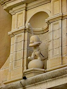 Fronton d'un bâtiment en pierre claire, orné d'une statue de Titeuf.