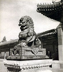 Photographie en noir et blanc d'une statue montrant un lion assis.
