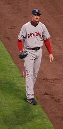 A man in a gray baseball uniform with a navy cap