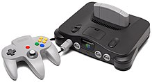 O controle do Nintendo 64 controller é cinza claro com três cabos para as duas mãos do jogador. O controle possui botões vermelhos, verdes, azuis e amarelos, uma alavanca analógica, e um direcional digital. O controle é conectado ao console cinza-chumbo com um cartucho cinza claro inserido. O console é convexo em seu topo e possui dois botões de força e quatro conectores de controle.