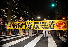 People protesting in the streets of Rio de Janeiro. The sign reads "Se a passagem nao baixar, o Rio vai parar!", which translates to "If the fare doesn't drop, Rio is going to stop!" Protestos no Rio em 2013.jpg
