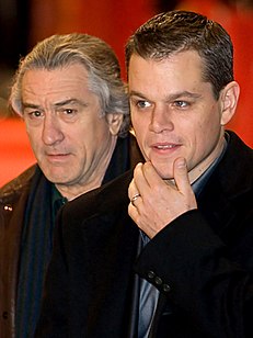 Photo of Damon and De Niro, each wearing a tuxedo jacket and a dark blue shirt.