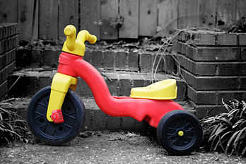 Tricycle d'enfant coloré en plastique sur un fond noir et blanc. (définition réelle 3 456 × 2 304)