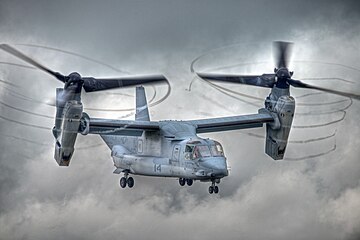 A Bell Boeing V-22 Osprey with rotors tilted and condensation trailing from the propeller tips