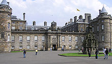 View of the Palace of Holyrood House showing the Royal Standard of Scotland flying from the rooftop flagpole, indicating that Her Majesty the Queen is not in residence.