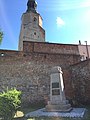 Mury Obronne z widocznymi zamurowanymi owalnymi oknami dawnych zabudowań zamkowych, w tle wieża zamkowa, na pierwszym planie pomnik 700- i 750-lecia Bierutowa