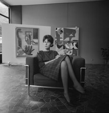 Schwarzweissfotografie, quadratisch, die Galeristin Heidi Weber sitzt im Damensessel LC3 von Le Corbusier, der von 1958 bis 1964 von ihr und später mit ihrer Lizenz von Cassina produziert wurde. Im Hintergrund links: Ölgemälde Les Lignes de la main von Le Corbusier, 1930, Mori Collection Tokyo, im Hintergrund rechts: Ölgemälde Taureau XV von Le Corbusier, 1957, Sammlung Heidi Weber