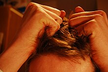 A boy pulling his hair is displayed