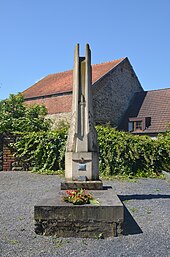Photographie d'un monument en pierre montrant des ailes verticales et une épée au centre.