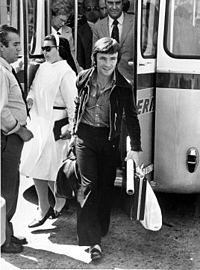 A black and white picture stepping out of a bus with briefcases in his hands.