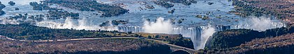 Vista aérea das Cataratas de Vitória do rio Zambeze, fronteira entre Zâmbia e Zimbábue. As Cataratas de Vitória são a maior cortina de água em queda do mundo ao combinar uma largura de 1 708 m e uma altura de 108 m. A imagem é o resultado de cinco fotografias tiradas de um helicóptero. (definição 11 686 × 2 172)