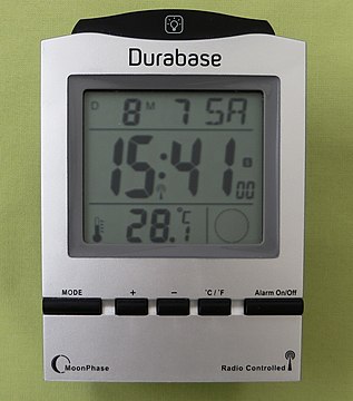 Wecker mit Flüssigkristall-Digitalanzeige. Neben der über Funk synchronisierten Zeit-, Datum- und Mondphasenanzeige auch Temperaturangabe.