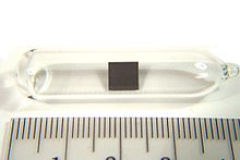 Small (3 cm) ampule with a tiny (5 mm) square of metal in it