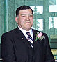 «Цветное изображение Тони Уитфорда, комиссара Северо-Западных территорий во время церемонии его приведения к присяге. Он в темном костюме и белой рубашке с галстуком и цветком в петлице».