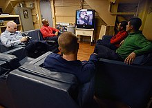 A group of people watching television US Navy 040515-N-6278K-081 Sailors take time out to watch television and relax in the Crew's Lounge located in the Ship's Library aboard USS George Washington (CVN 73).jpg