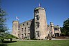 Huge stone-built castle with rounded towers and flags on top