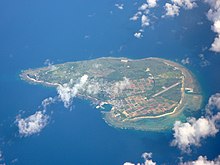 Vue aérienne couleur d'une île, dans une étendue d'eau bleue.