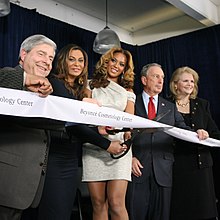 A woman is surrounded by several others, all behind a piece of white tape