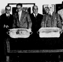 Photograph of four men, two of who are holding silver trays.