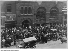 Crowd of people in the street in front of a brick building