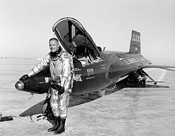 A black-and-white photo of Armstrong smiling outside of an X-15