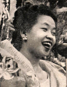 A smiling Philipina woman, her dark hair in an updo