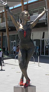 Бронзовая статуя Кайли на пьедестале в форме звезды изображает ее в танцующей позе. Ее ноги скрещены, она сгибается в талии, подняв обе руки над головой. Статуя стоит на городской площади перед современным стеклянным зданием, по нему идет несколько человек.