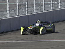 Photographie d'une monoplace de Formule E grise et verte, vue de trois-quarts, dans son ensemble.