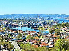 Foto einer an einer Flussmündung gelegenen Stadt mit Wohnsiedlungen im Vordergrund und einem Industriegebiet im Hintergrund