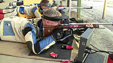 Colour photograph of a man firing a rifle.