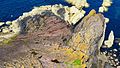 The rugged point, seen from above, shows gently sloping beds of red sandstone above vertical beds of greywacke, forming a classic example of Hutton's Unconformity.