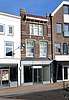 Winkel/woonhuis met overstekende bakgoot en gedecoreerde steunen in Chaletstijl (Gouda-Centrum)