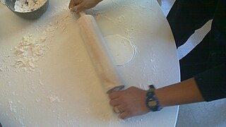 Rolling out the batter with a rolling pin.