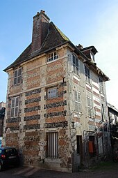 Photographie en couleurs d'une bâtiments à étages avec lits alternés de moellons bruns et de briques roses.