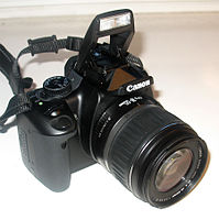 Die Canon EOS 400D met 'n EF-S 18-55mm std. uitrustinglens en nekband