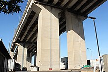 画像左:金城高架橋（工事中の名称は名港西大橋高架橋）。道路規格アップのため両側に拡幅された[279]。 画像右:金城高架橋の橋脚は短形断面として四隅を面取りした。橋脚中央にはスリットを設け、その中に排水管を設置した。
