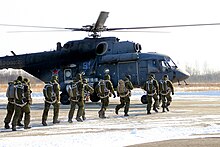 File d'hommes en uniforme devant un hélicoptère militaire