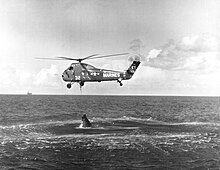 HUS-1 helicopter attempting to recover the Liberty Bell 7 spacecraft. The recovery ship USS Randolph is visible in the distance. Failed Attempt to Recover Liberty Bell 7 - GPN-2002-000047.jpg