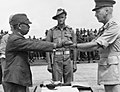 1945年9月、オーストラリア陸軍中将ホレス・ロバートソンに対し、降伏の証として自身の軍刀（昭9制/昭13制刀）を手渡す陸軍中将安達二十三第18軍司令官