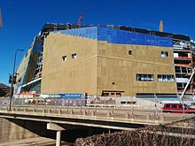 From directly east of the stadium: the southeast facade with doors and windows going in, as well as the northeast facade with part of its exterior wall up. New Minnesota Stadium 13 April 2015.jpg