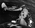 Two Curtiss SB2C-3 "Helldiver" aircraft bank over the USS Hornet in 1945, in a photo by Lt Cmdr Charles Kerlee