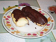 Picture of two éclairs: one is cut in half, and both are originally longish loaves of pastry with a cream filling, topped with chocolate.
