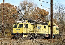 A railway work vehicles in bright yellow paint with a blue Amtrak logo