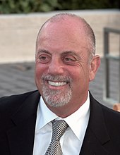 A balding man with a grey beard wearing a necktie