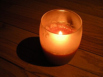 English: An orange candle burning in a dark en...