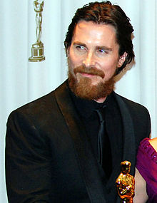 Christian Bale in a black suit at a movie premiere.