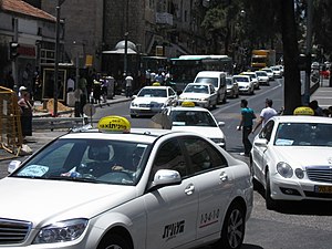 Israeli white taxis traveling the noontime str...